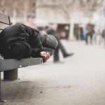 Person sleeping on a bench in a public area