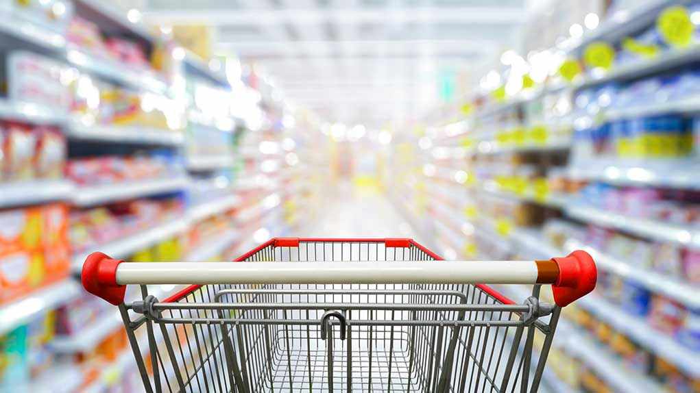 Shopping cart in aisle of grocery store