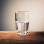 Glass of water half full on table