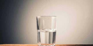 Glass of water half full on table