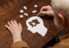 Elderly person completing head-shaped jigsaw puzzle