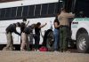 Border patrol officers investigating people near a bus