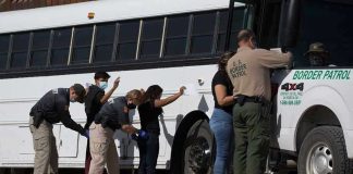 Border patrol officers investigating people near a bus