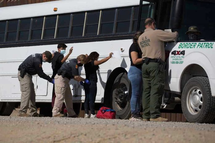 1973414852 Border patrol officers investigating people near a bus