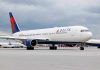 Delta Airlines airplane on airport runway, cloudy sky