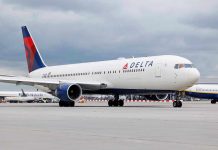 Delta Airlines airplane on airport runway, cloudy sky