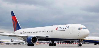 Delta Airlines airplane on airport runway, cloudy sky