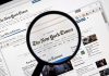 Magnifying glass over The New York Times website.