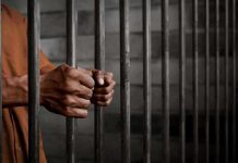 Hands gripping prison cell bars