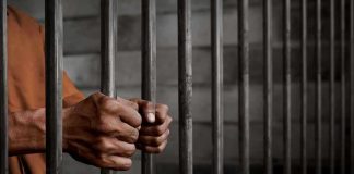Hands gripping prison cell bars