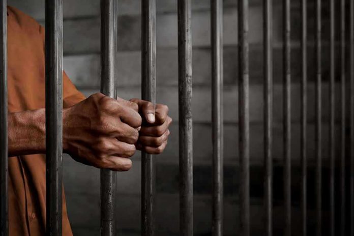 772489252 Hands gripping prison cell bars
