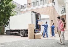 Workers unloading boxes from a moving truck in a residential driveway