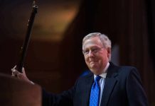 A man in a suit holding a gavel at a podium