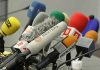 A collection of various microphones arranged for a press conference