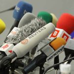 A collection of various microphones arranged for a press conference