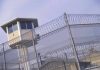 Guard tower behind barbed wire fence in a prison