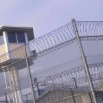Guard tower behind barbed wire fence in a prison
