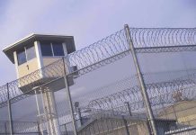 Guard tower behind barbed wire fence in a prison