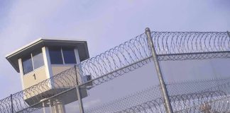 Guard tower behind barbed wire fence in a prison