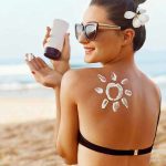 Woman applying sunscreen at the beach.
