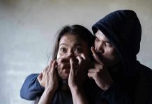 Man holding woman's mouth, gesturing silence.