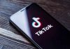 Phone screen showing TikTok logo and app.