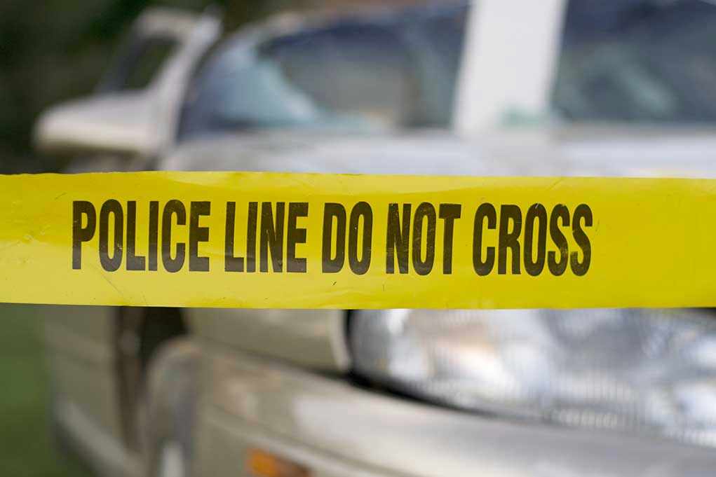 Yellow police tape in front of a car.