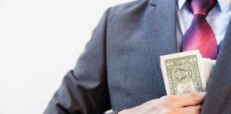 Person in suit putting money in jacket pocket.