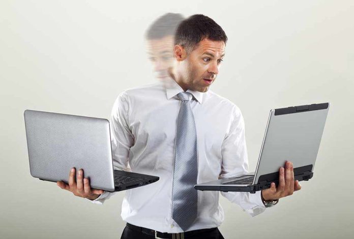 532697098 Man holding two laptops and looking surprised