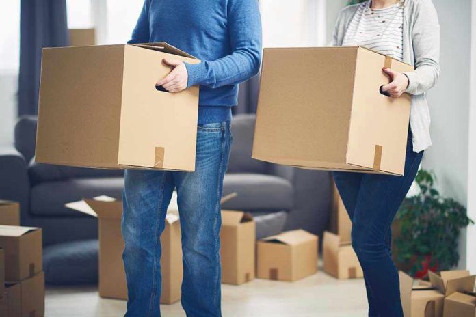 567850450 Two people carrying cardboard boxes indoors