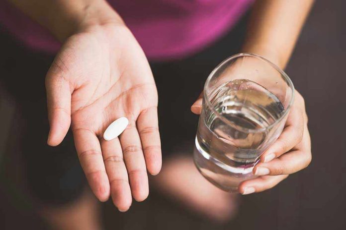 718784776 Person holding pill and glass of water