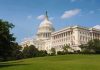 The U.S. Capitol building surrounded by green grass and trees under a blue sky