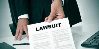 Person holding a document titled LAWSUIT in office.