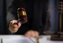 Hand holding gavel in courtroom setting.