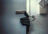 Gloved hand opening door with security chain.