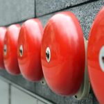 Row of red alarm bells mounted on a wall