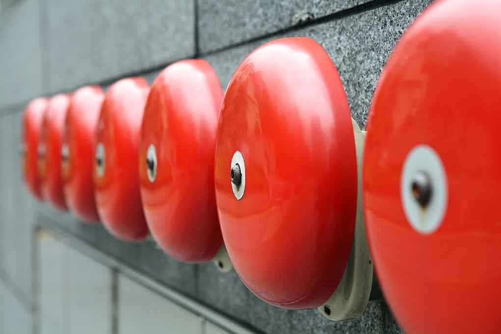 Row of red alarm bells mounted on a wall