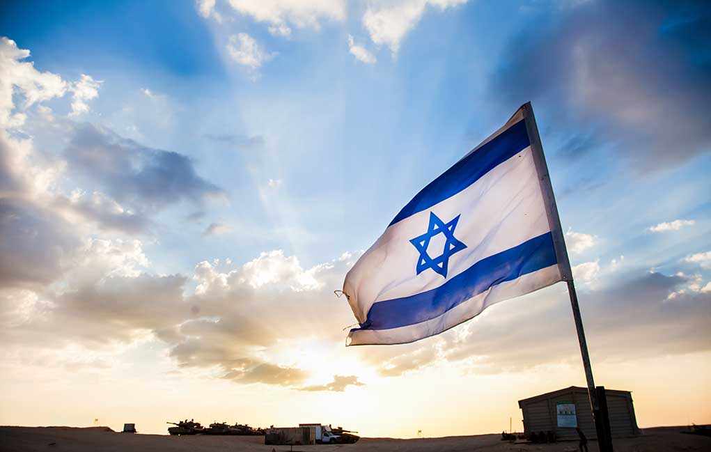 Israeli flag waving against a sunset backdrop with clouds
