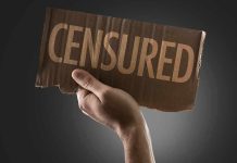 A hand holding a cardboard sign that reads CENSORED