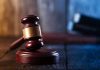 Gavel on wooden table in dimly lit room.