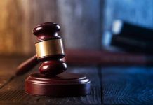 Gavel on wooden table in dimly lit room.