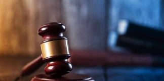 Gavel on wooden table in dimly lit room.