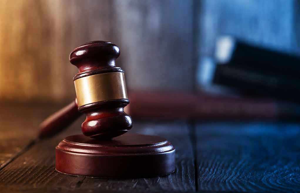 Gavel on wooden table in dimly lit room.