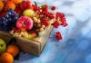 A wooden crate filled with a variety of fresh fruits including apples, grapes, and berries