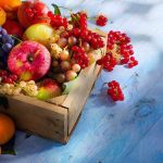 A wooden crate filled with a variety of fresh fruits including apples, grapes, and berries
