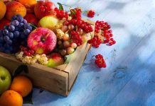 A wooden crate filled with a variety of fresh fruits including apples, grapes, and berries