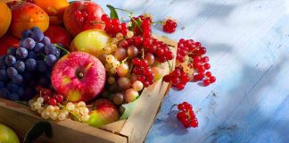 A wooden crate filled with a variety of fresh fruits including apples, grapes, and berries