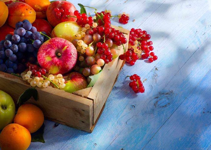 A wooden crate filled with a variety of fresh fruits including apples, grapes, and berries
