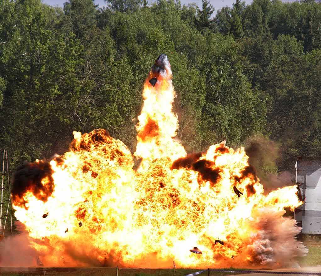A large explosion with flames and smoke in an outdoor setting